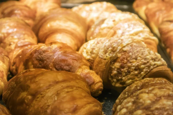 A number of appetizing ruddy croissants on a tray in a showcase