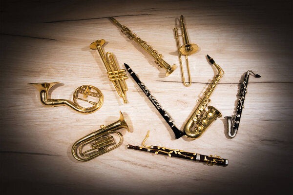 A number of toy wind instruments  lying on a wooden board, dark vignette