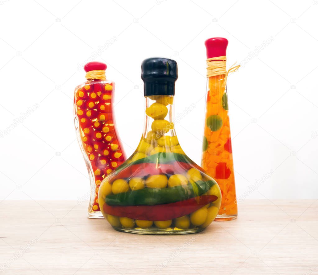 Three decorative glass sealed bottles of different shapes with colorful vegetables inside
