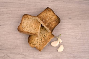 Ekmek dilimleri iştah gevrek kabuk ve ahşap tahta üzerinde birkaç diş sarımsak ile