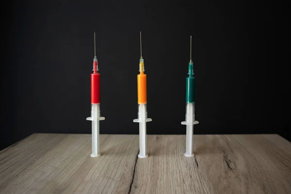 Три Медицинских Шприца Цветной Жидкостью Стоящие Прямо Деревянной Доске — стоковое фото