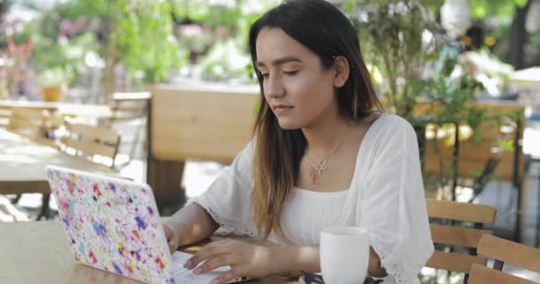 Mujer sentada trabajando en una cafetería al aire libre — Vídeo de stock