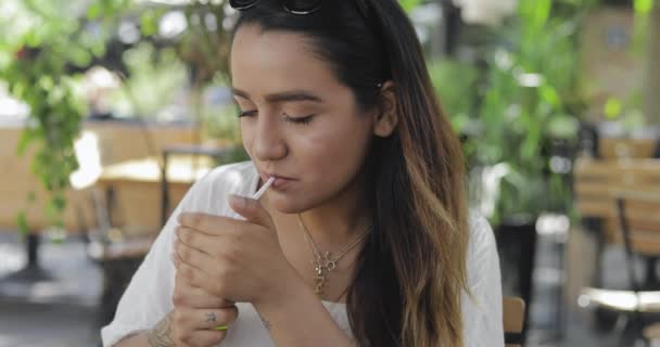 Молодая женщина закуривает сигарету — стоковое видео