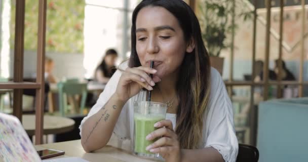 Wanita muda meminum smoothie hijau yang sehat — Stok Video