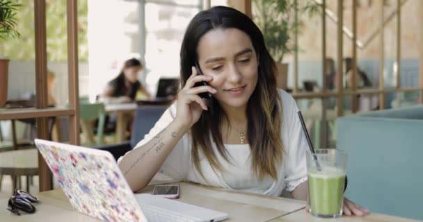 Mujer joven sentada escuchando una llamada móvil — Vídeos de Stock