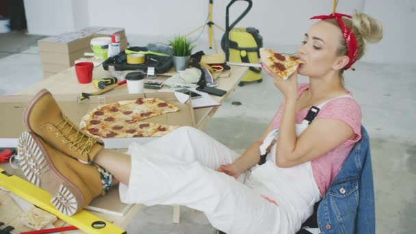 İş yerinde pizza yiyen kadın marangoz. — Stok video