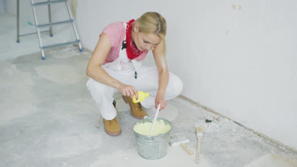 Mujer mezclando pintura de pared en cubo — Vídeos de Stock