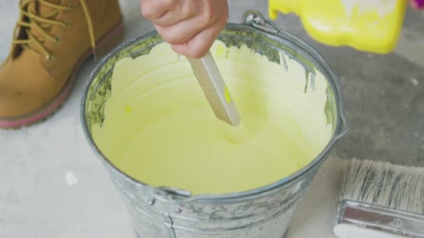 Hand mixing yellow wall paint in bucket — Stock Video