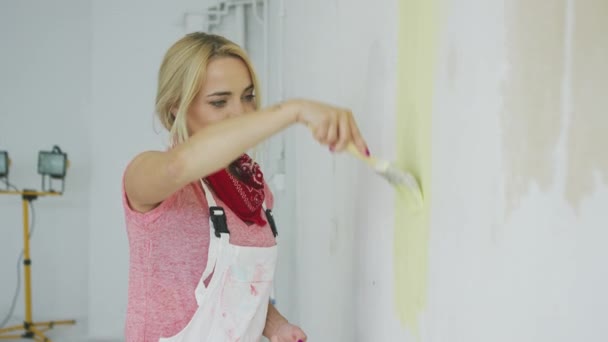 Mujer sonriente pintura pared amarillo — Vídeos de Stock