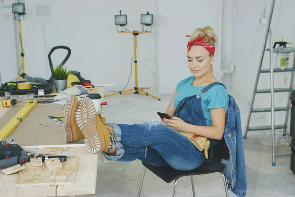 Mulher descansando com smartphone na bancada de carpinteiro — Fotografia de Stock