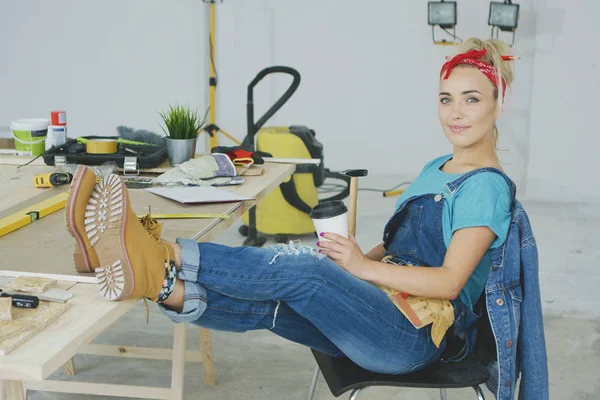 Feminino relaxante na bancada de carpinteiro com bebida — Fotografia de Stock