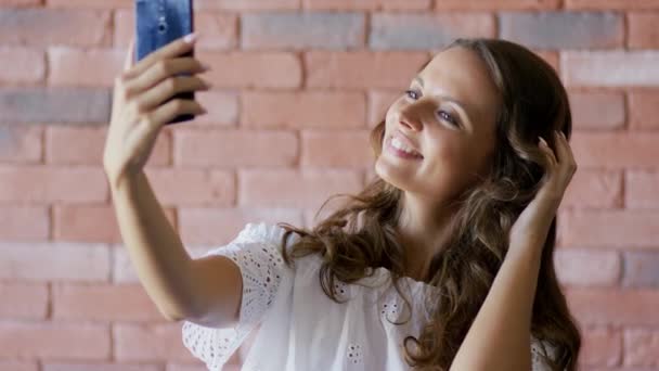 Mujer joven tocando el cabello y tomando selfie — Vídeos de Stock