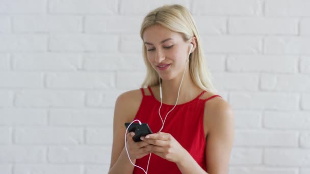 Ładna kobieta słuchanie muzyki i przy użyciu smartfona — Wideo stockowe