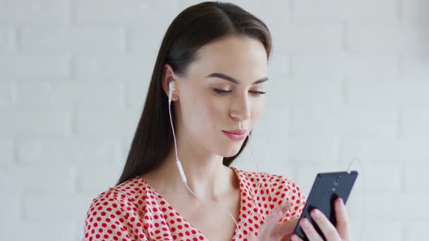 Mujer linda escuchando música y utilizando el teléfono inteligente — Vídeo de stock