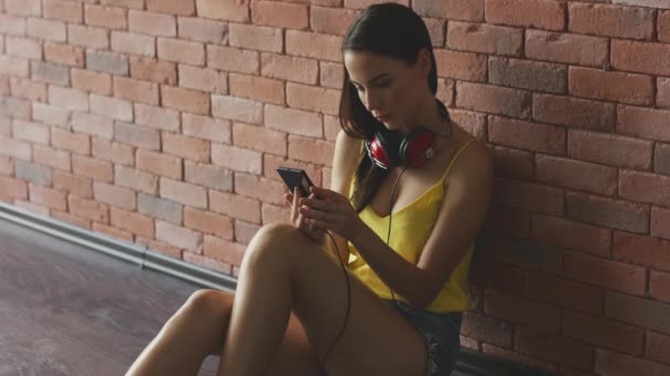 Mujer joven usando teléfono inteligente cerca de la pared — Vídeos de Stock