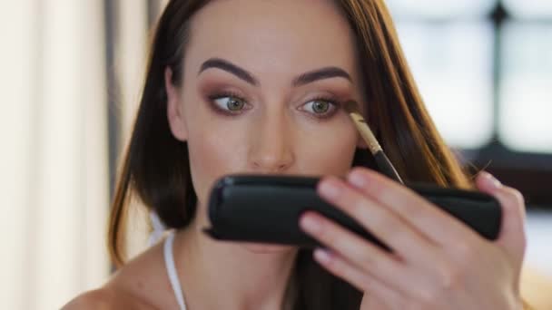 Mujer joven aplicando sombra de ojos — Vídeos de Stock