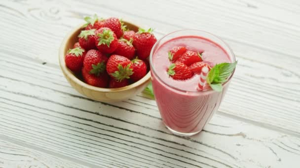 Glass with smoothie and bowl of strawberries — Stock Video