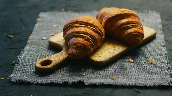 Croissants frescos sobre tabla de cortar —  Fotos de Stock