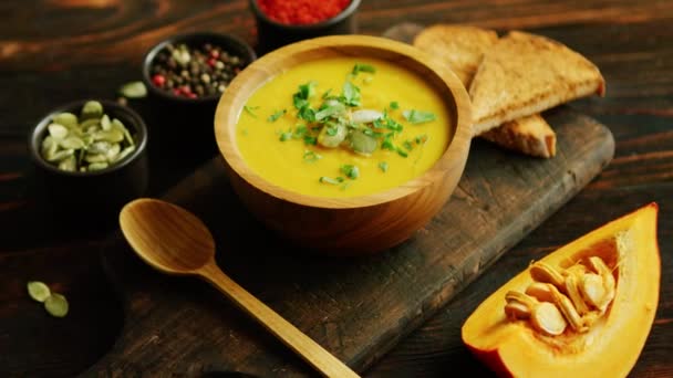 Fresh pumpkin soup in bowl on chopping board — Stock Video