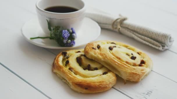 Delicious pastry with raisins and a cup of coffee top view. — Stock Video