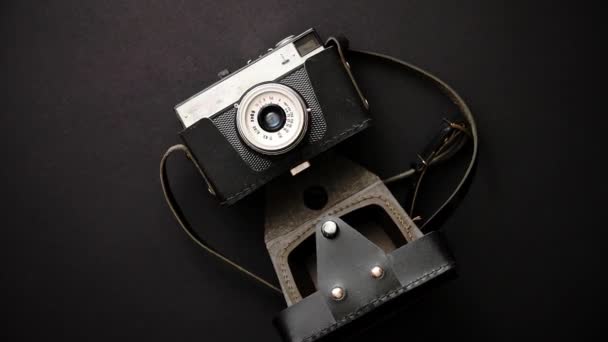 Old retro film camera in leather case on black background — Stock Video