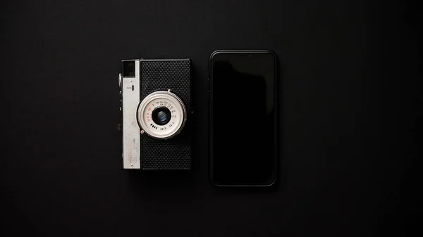 Старая ретро-камера и современный смартфон на черном фоне — стоковое фото