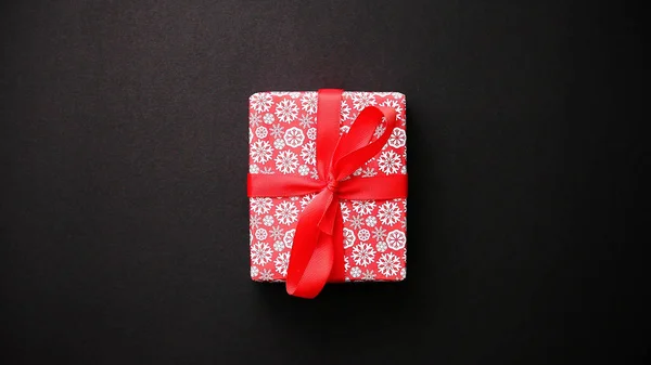 Coffret cadeau rouge avec noeud rouge sur table noire, vue de dessus — Photo