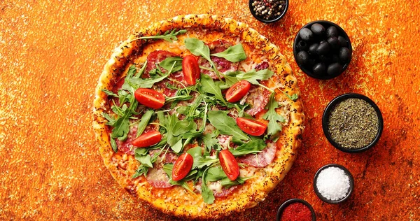 Välsmakande pizza på en rostig bakgrund med kryddor, örter och grönsaker — Stockfoto