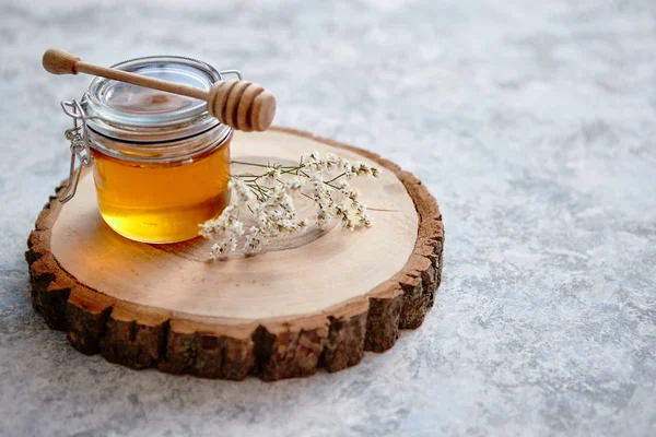 Glazen pot vol met verse honing geplaatst op slice van hout — Stockfoto