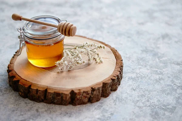 Pot en verre rempli de miel frais placé sur une tranche de bois — Photo