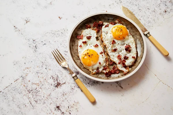 Twee verse gebakken eieren met knapperig knapperig spek geserveerd op rustieke bord — Stockfoto