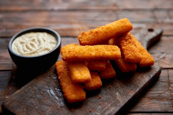 Pile of golden fried fish fingers with white garlic sauce — Stock Photo, Image