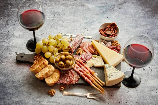 Tavola degli snack freddi con salumi, uva, vino, vari tipi di formaggio — Foto Stock