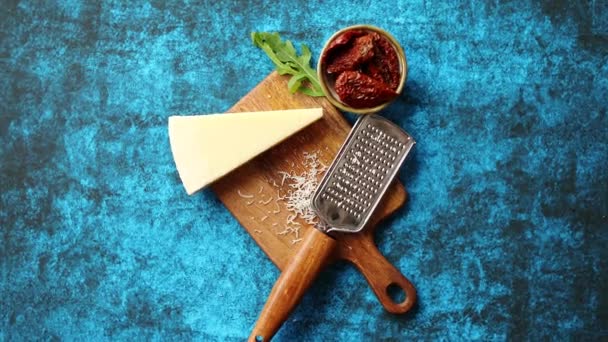 Rallador clásico rallado de queso parmesano y metal colocado en una tabla de cortar de madera — Vídeo de stock