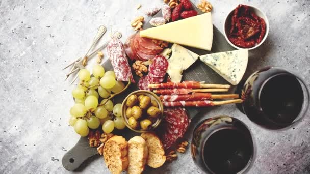Soğuk abur cubur tahtasında et, üzüm, şarap ve çeşitli peynir var. — Stok video