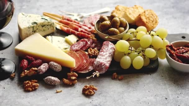 Tablero de aperitivos fríos con carnes, uvas, vino, varios tipos de queso — Vídeos de Stock