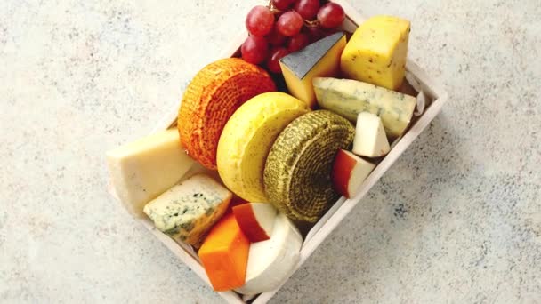 Свежие и вкусные различные виды сыров, помещенных в деревянный ящик с виноградом — стоковое видео