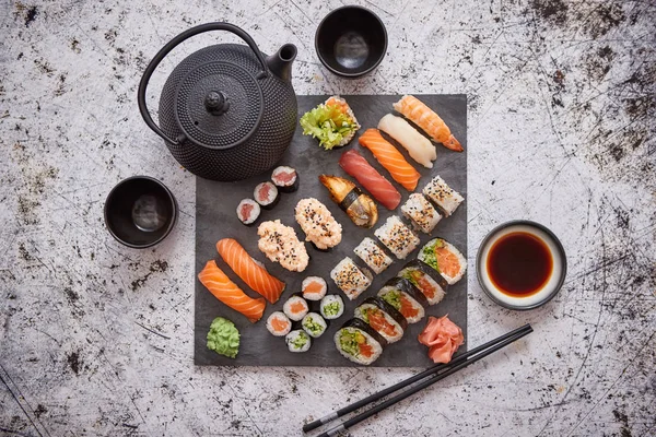 Választék a különböző típusú sushi tekercs elhelyezett fekete kő táblán — Stock Fotó
