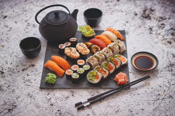 Surtido de diferentes tipos de rollos de sushi colocados en tablero de piedra negro — Foto de Stock