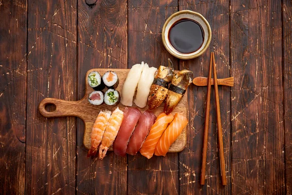 Set de Sushi. Diferentes tipos de rollos de sushi en tablero de servir de madera — Foto de Stock