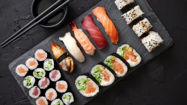 Set de rollos de sushi con salmón y atún servido en tablero de piedra negra — Vídeos de Stock