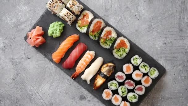 Rolos de sushi conjunto com salmão e atum peixes servidos na placa de pedra preta — Vídeo de Stock