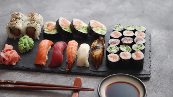 Složení různých druhů sushi válců umístěných na černé kamenné desce — Stock video