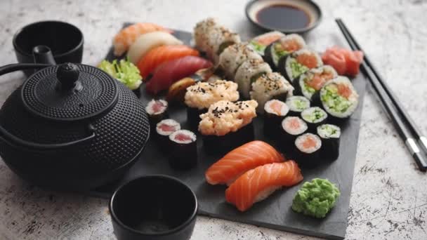 Választék a különböző típusú sushi tekercs elhelyezett fekete kő táblán — Stock videók