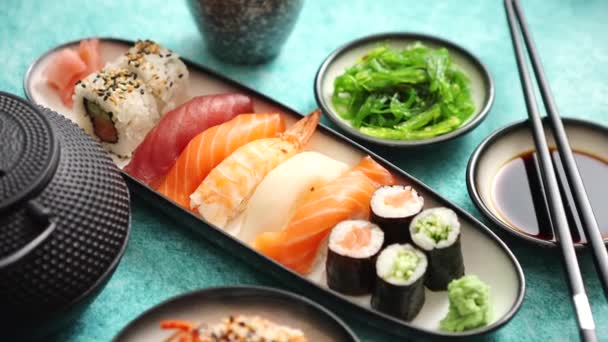 Asijský sortiment potravin. Různé sushi role umístěné na keramických deskách — Stock video