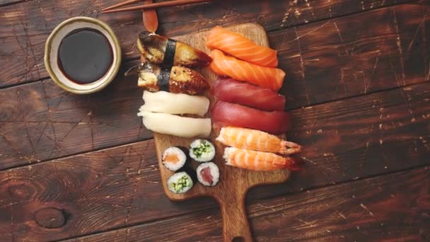 Суши сет. Различные виды суши-рулонов на деревянной доске — стоковое видео