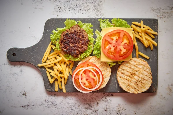 Zwei leckere gegrillte hausgemachte Burger mit Rindfleisch, Tomaten, Zwiebeln und Salat — Stockfoto