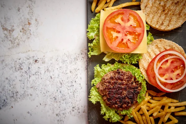 Dois saborosos hambúrgueres caseiros grelhados com carne, tomate, cebola e alface — Fotografia de Stock