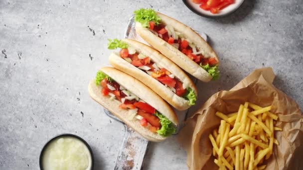 Tres perritos calientes a la parrilla con salchichas colocadas en una tabla de cortar de madera — Vídeos de Stock