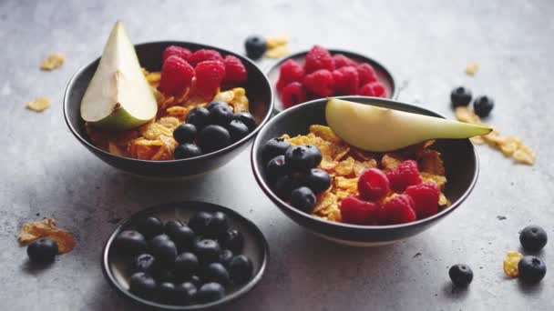 Copos de maíz dorados con frutas frescas de frambuesas, arándanos y pera en tazón de cerámica — Vídeos de Stock